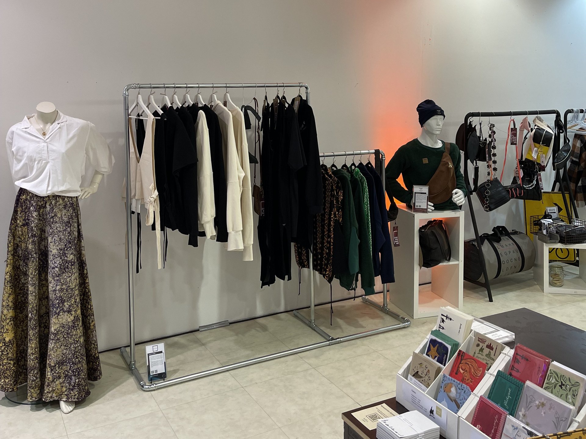 Innenansicht des PopUp-Stores mit Kleiderstangen und Puppen, die die Produkte präsentieren vor einem weißen Hintergrund.