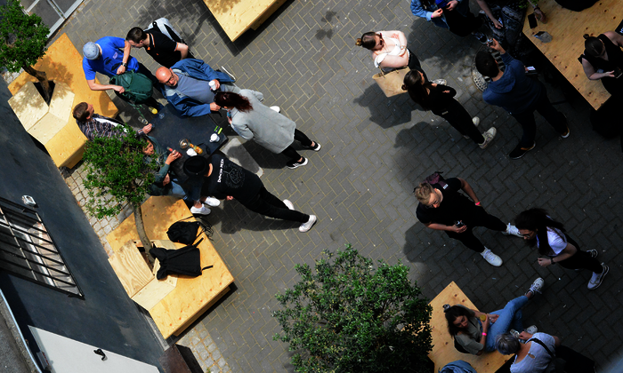 Menschen in einem Innenhof im Sommer, die sich unterhalten und in der Sonne sitzen.