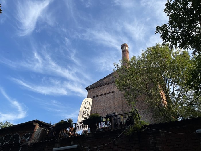 Man sieht die Terrasse vom Gretchen Biergarten mit blauem Himmel im Hintergrund und eine kreHtiv Flagge darauf.