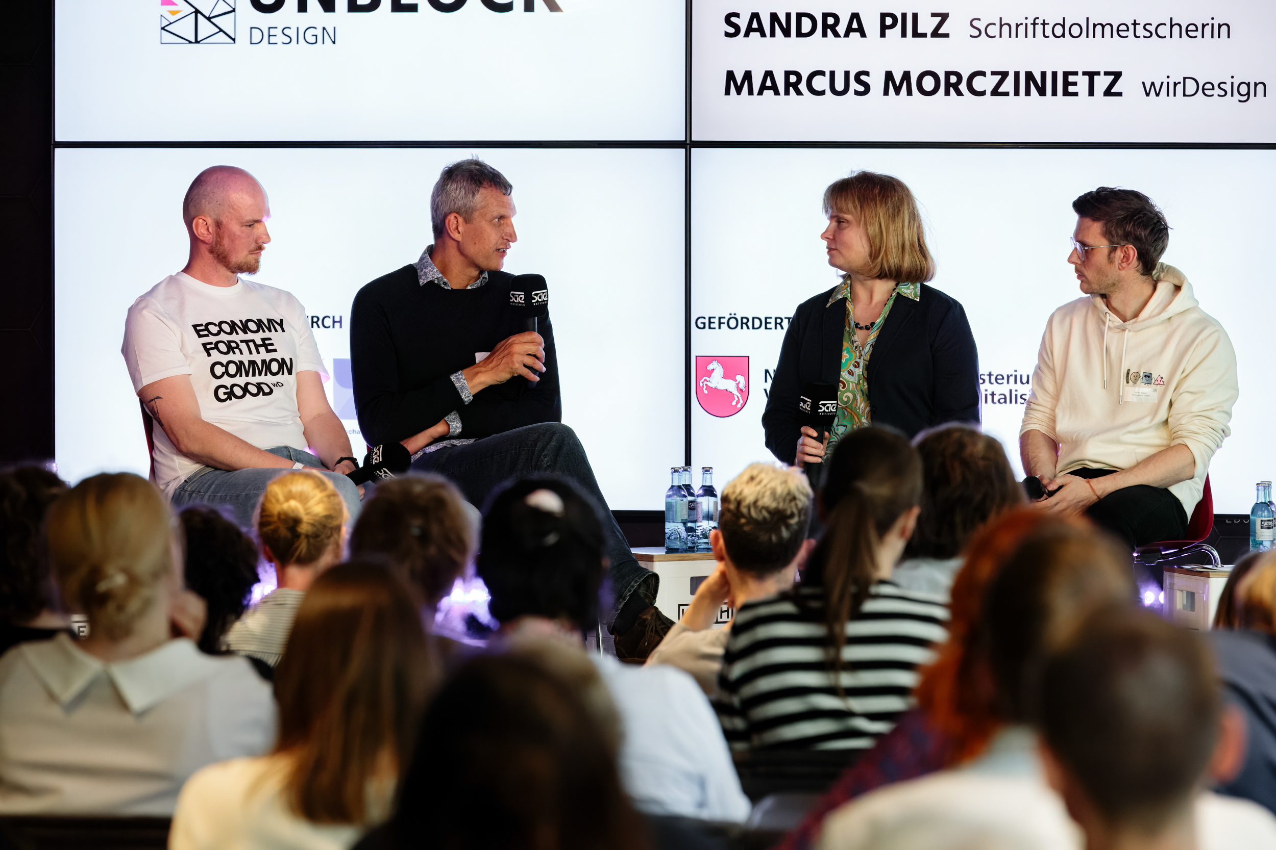 Drei Männer und eine Frau auf einer Paneldiskussion.
